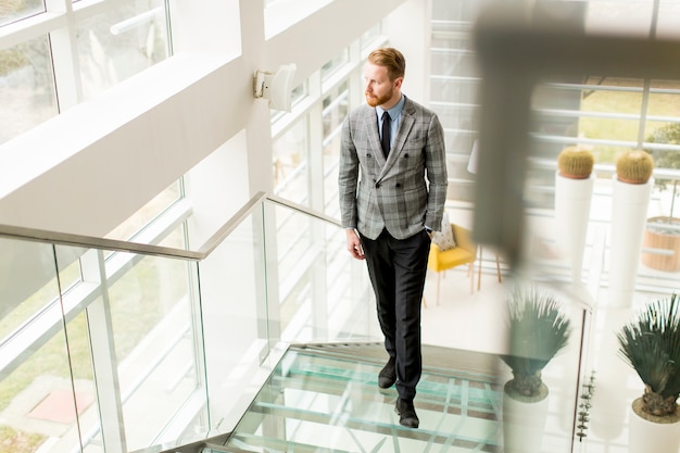 Young businessman going up the stairs in the office building