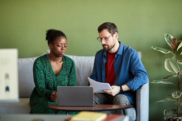 Young businessman and his african american colleague in smart casualwear watching and discussing onl