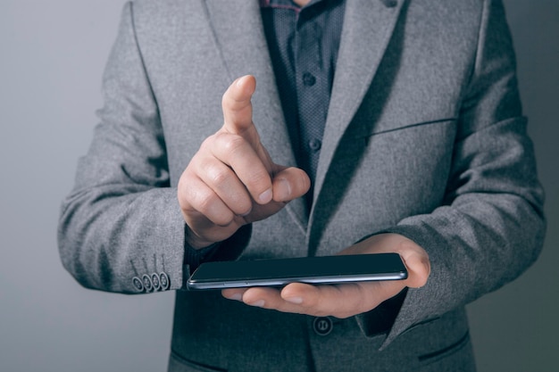 young businessman holding a phone and clicking on a virtual screen