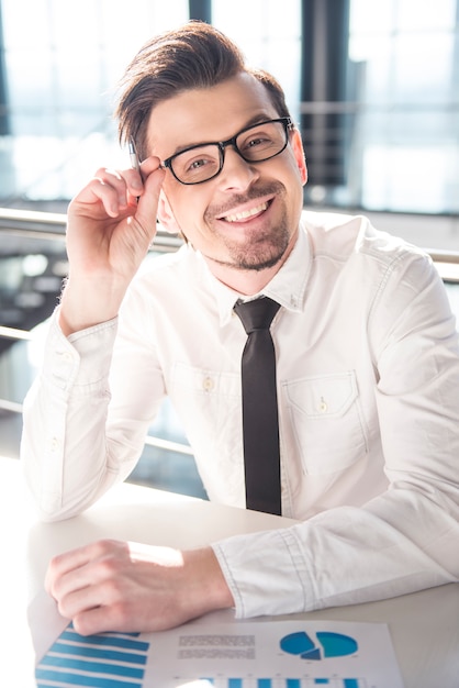 Young businessman is sitting at the table with documents.