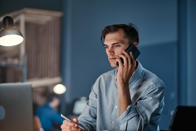 Young businessman making a call from the office at night