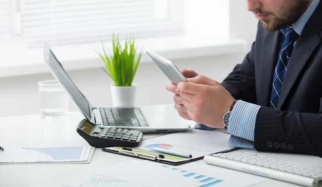 Young businessman in office with smartphone tablet at workplace