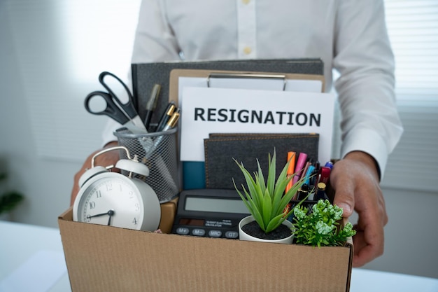 Young businessman puts personal belongings in a box after sending resignation letter Employees were fired from jobs Change position and move functions