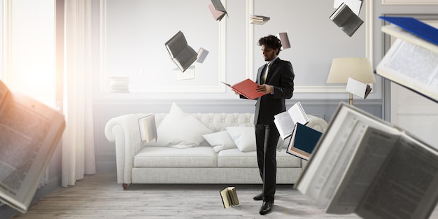 Young businessman reading a book with lots of books flying around. Mixed media