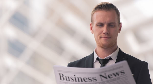 Young businessman reading a Newspaper news in the morning.