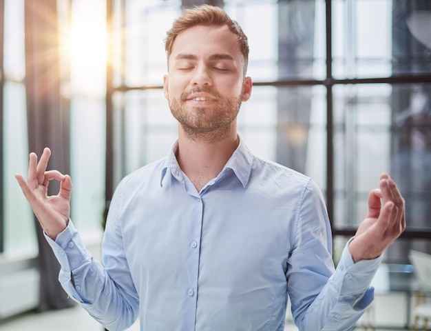 Photo young businessman relaxing while standing in the office