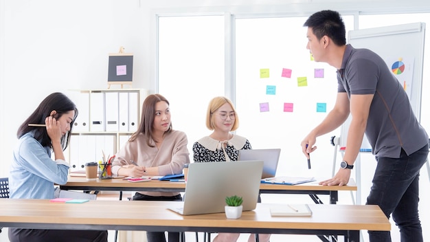 A young businessman's boss is meeting with a young employee in a meeting room.