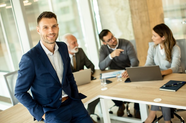 Young businessman standing in front of his coleagues in the office