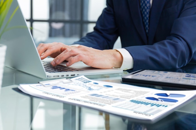 Young businessman typing computer laptop with graph chart for work