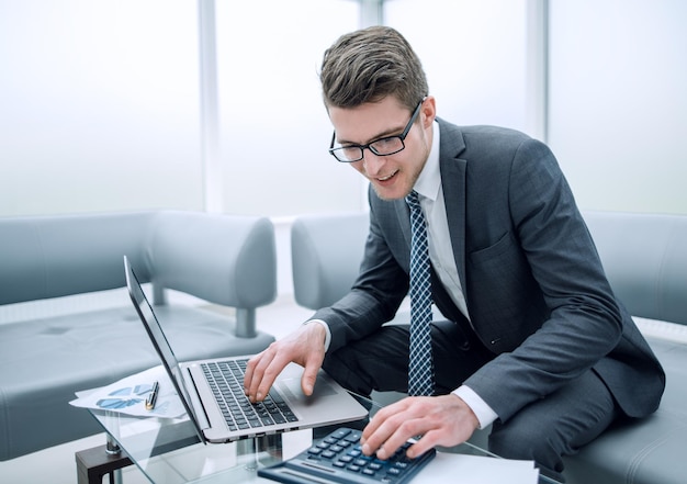 Young businessman using calculator and laptop  photo with copy space