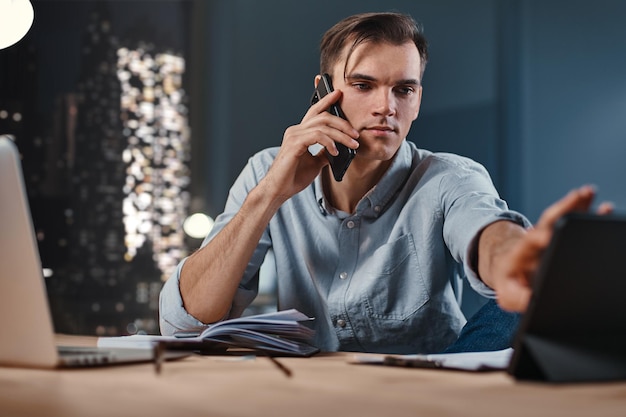 Young businessman using a smartphone and a digital tablet in the workplace