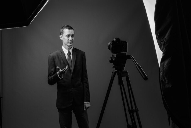 Photo young businessman wearing suit against gray wall in black and white