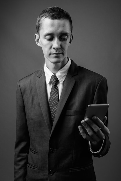  young businessman wearing suit against gray wall in black and white