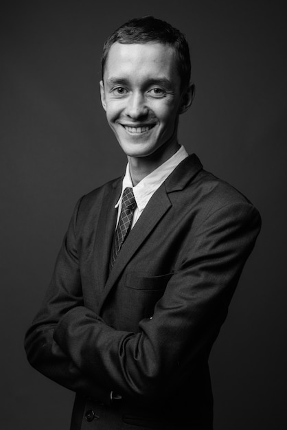  young businessman wearing suit against gray wall in black and white