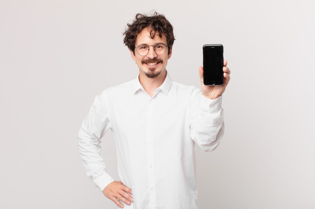 Young businessman with a cell smiling happily with a hand on hip and confident