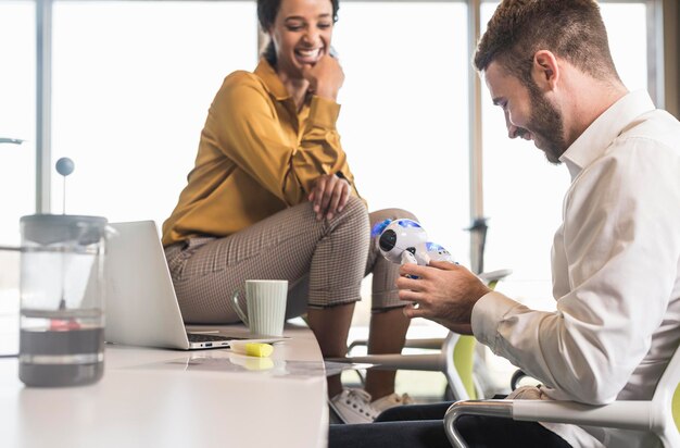 Photo young businessman with colleague in office holding robot