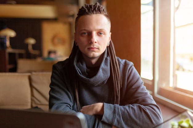 Young Businessman with dreadlock having doing his work in cafe with laptop.