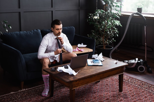 Young businessman without pants during job interview or online meeting during distant work from home