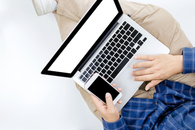 Young businessman working at laptop computer with smartphone