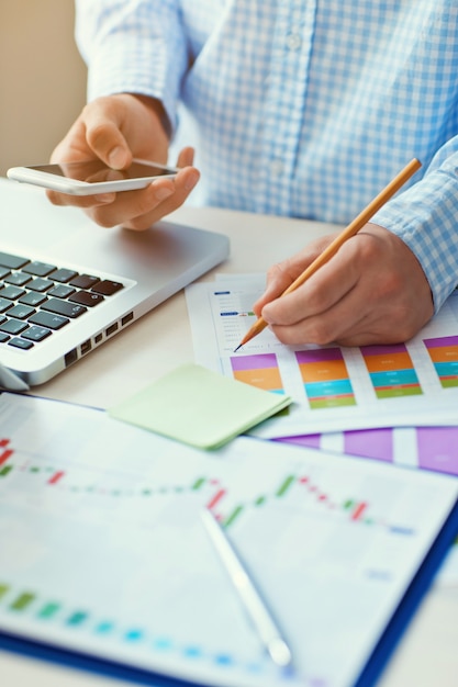 Young businessman working  in the office. Notebook on wood table, papers, documents, statistics