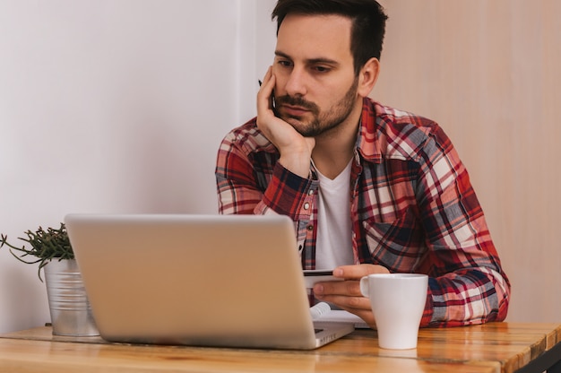 Young businessman working in office, sitting at desk and looking at laptop computer screen