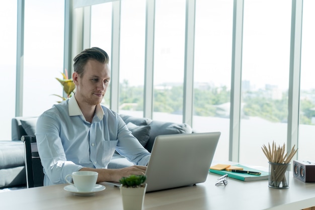 young businessman in working with laptop notebook computer remotelysitting at table in living room