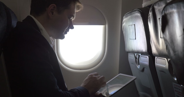 Young businessman working with pad in plane