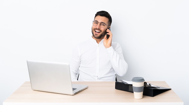 Young businessman in a workplace keeping a conversation with the mobile phone