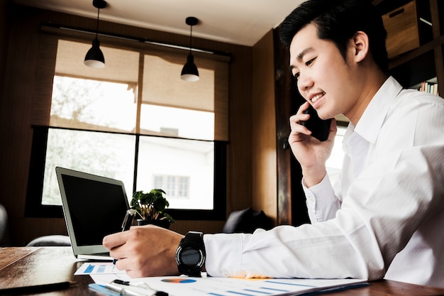 Young businessmen work with mobile phones and notebooks in the office.