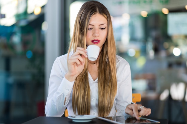 Young businesswoman on a coffee break. Using tablet computer.