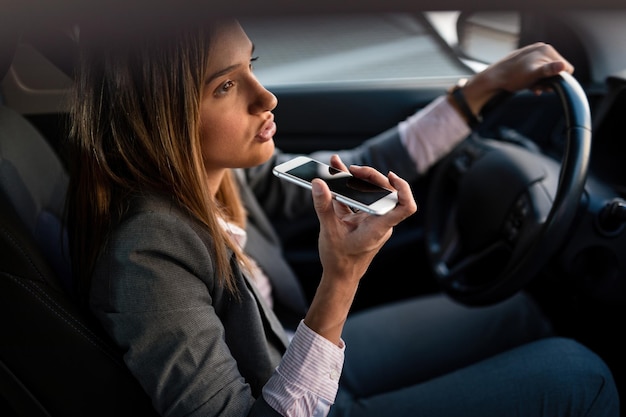 Young businesswoman commuting to work and talking on mobile phone while driving a car