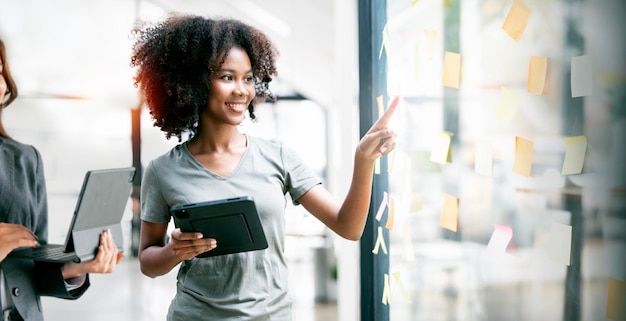 Young businesswoman creative team using post it notes in glass wall to writing strategy business plan to development grow to successx9