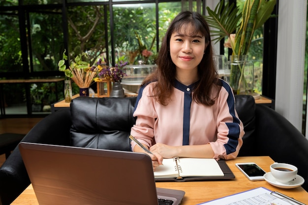 Young businesswoman doing some paperwork while sitting in front of laptop in home office.