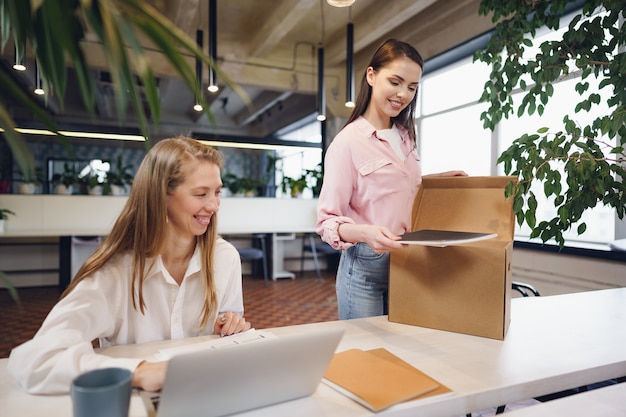 Young businesswoman holding box of personal belongings about to leave office after quitting job