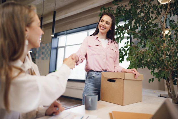 Young businesswoman holding box of personal belongings about to leave office after quitting job