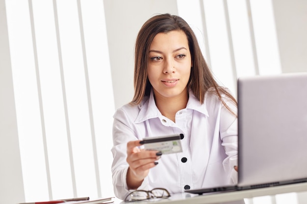 Young businesswoman holding a credit card and looking at the laptop.