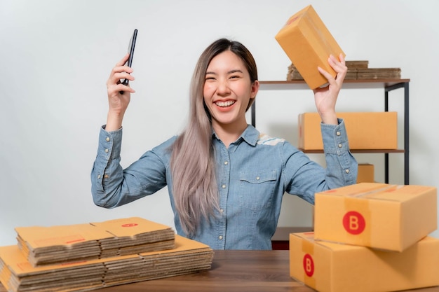 A young businesswoman is very happy after checking her email through her laptopOnline sellers are packing products into parcel boxes