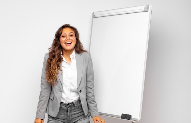 Young businesswoman looking happy and pleasantly surprised, excited with a fascinated and shocked expression