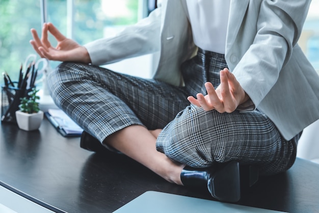 Young businesswoman meditating in office