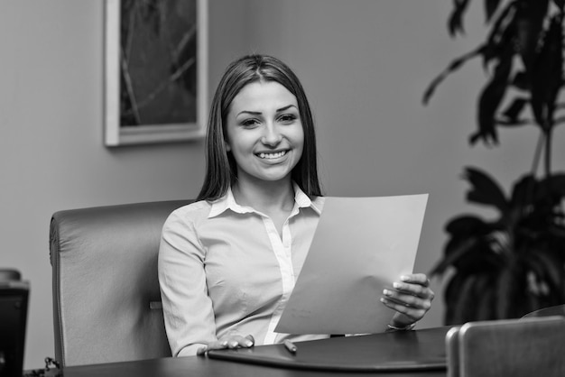 Young Businesswoman In Office Looking At Paper