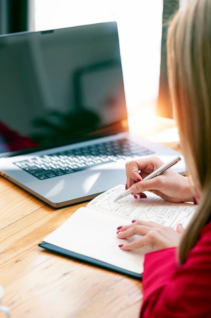 Young businesswoman in red suit writing business plan at her office desk