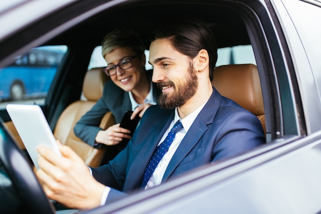 Young businesswoman sitting in limousine and talking with her driver. Business concept.