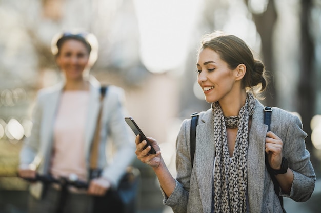 A young businesswoman surfing the net on a smartphone while going to work.