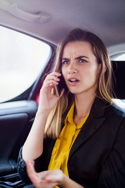 Young businesswoman talking on mobile phone in car