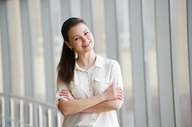 Young businesswoman talking on mobile phone while standing by window in office. Beautiful young female model in office.