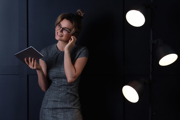 Young businesswoman using wireless earbuds and tablet pc during late night work in office