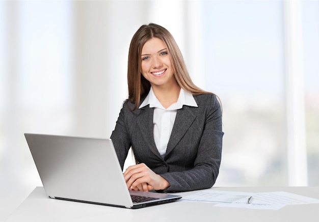 Young businesswoman with laptop on blurred background