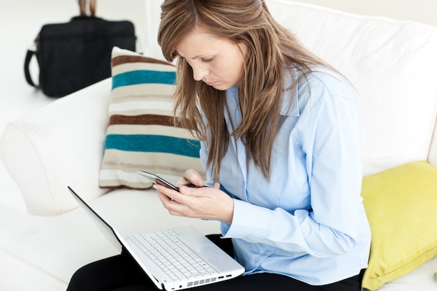 Young businesswoman with laptop and cellphone