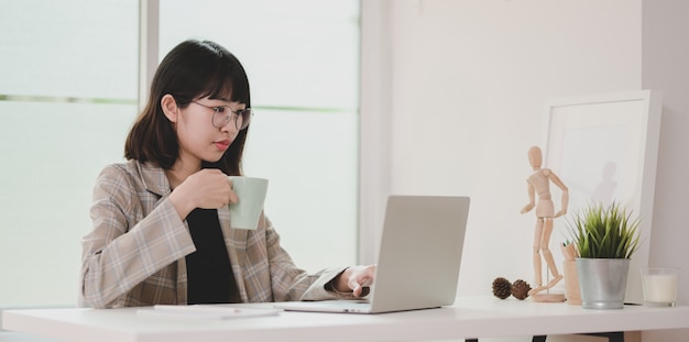 Young businesswoman working on her project while drinking coffee 