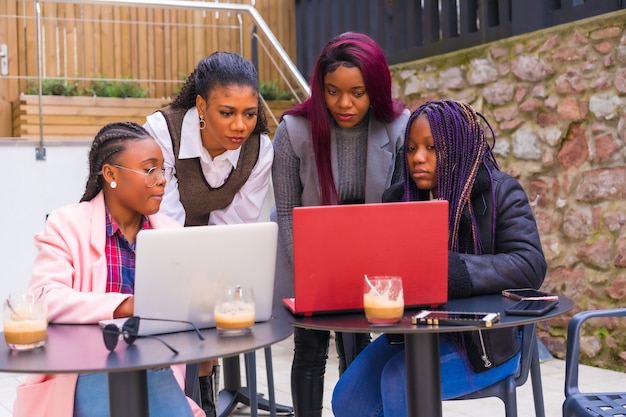 Young businesswomen of black ethnicity. In a teamwork meeting, in a cafeteria with computers, looking carefully at the screens